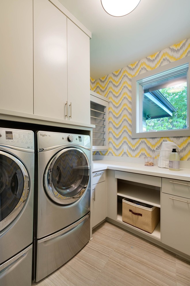Kleine Moderne Waschküche in L-Form mit Einbauwaschbecken, flächenbündigen Schrankfronten, Mineralwerkstoff-Arbeitsplatte, Keramikboden, Waschmaschine und Trockner nebeneinander, beigen Schränken und bunten Wänden in Minneapolis
