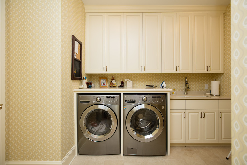 ミネアポリスにある広いトラディショナルスタイルのおしゃれな洗濯室 (I型、シングルシンク、レイズドパネル扉のキャビネット、白いキャビネット、黄色い壁、左右配置の洗濯機・乾燥機) の写真