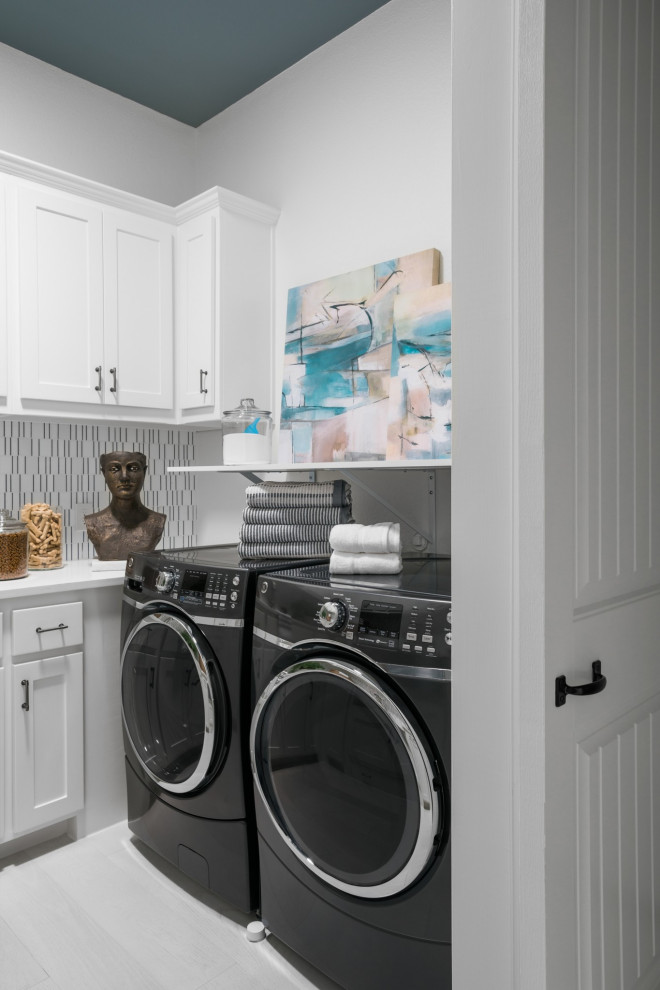 Example of a mid-sized minimalist u-shaped light wood floor and white floor dedicated laundry room design in Chicago with a drop-in sink, raised-panel cabinets, white cabinets, quartzite countertops, white walls, a side-by-side washer/dryer and white countertops
