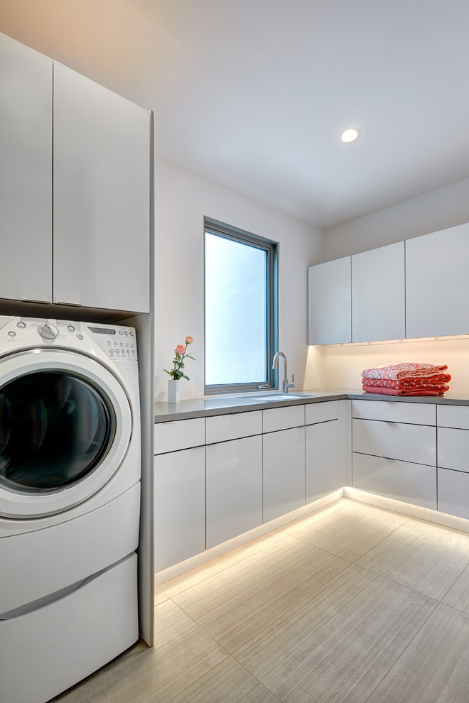 Inspiration för mellanstora moderna l-formade grått tvättstugor enbart för tvätt, med en undermonterad diskho, släta luckor, vita skåp, bänkskiva i kvarts, vita väggar, klinkergolv i porslin och en tvättmaskin och torktumlare bredvid varandra