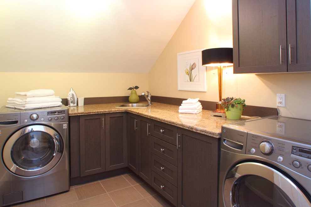 Example of a large transitional l-shaped porcelain tile dedicated laundry room design in Calgary with a drop-in sink, recessed-panel cabinets, dark wood cabinets, granite countertops, beige walls and a side-by-side washer/dryer