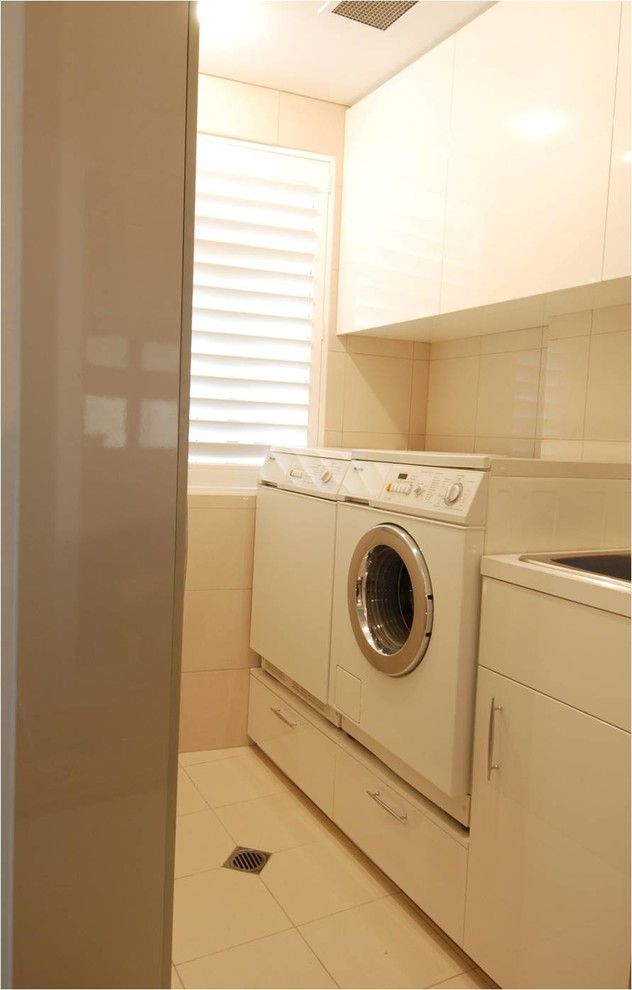 Esempio di una piccola sala lavanderia minimalista con ante lisce, ante beige, pareti bianche, lavatrice e asciugatrice affiancate, pavimento bianco e lavello da incasso