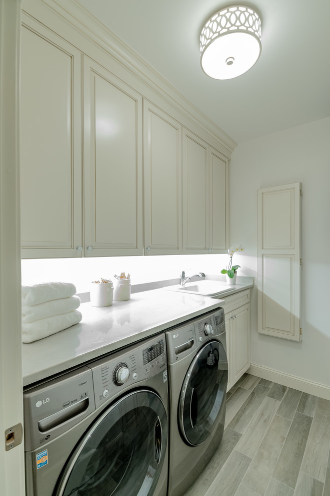 Design ideas for a small classic single-wall separated utility room in Philadelphia with a built-in sink, beaded cabinets, white cabinets, quartz worktops, white walls, a side by side washer and dryer, grey floors and grey worktops.