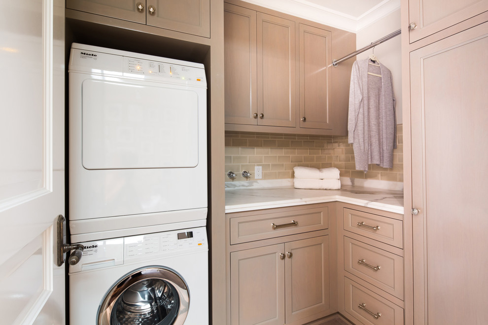 Diseño de lavadero en L tradicional pequeño con armarios con paneles empotrados, puertas de armario de madera clara, paredes blancas, lavadora y secadora apiladas y encimeras blancas