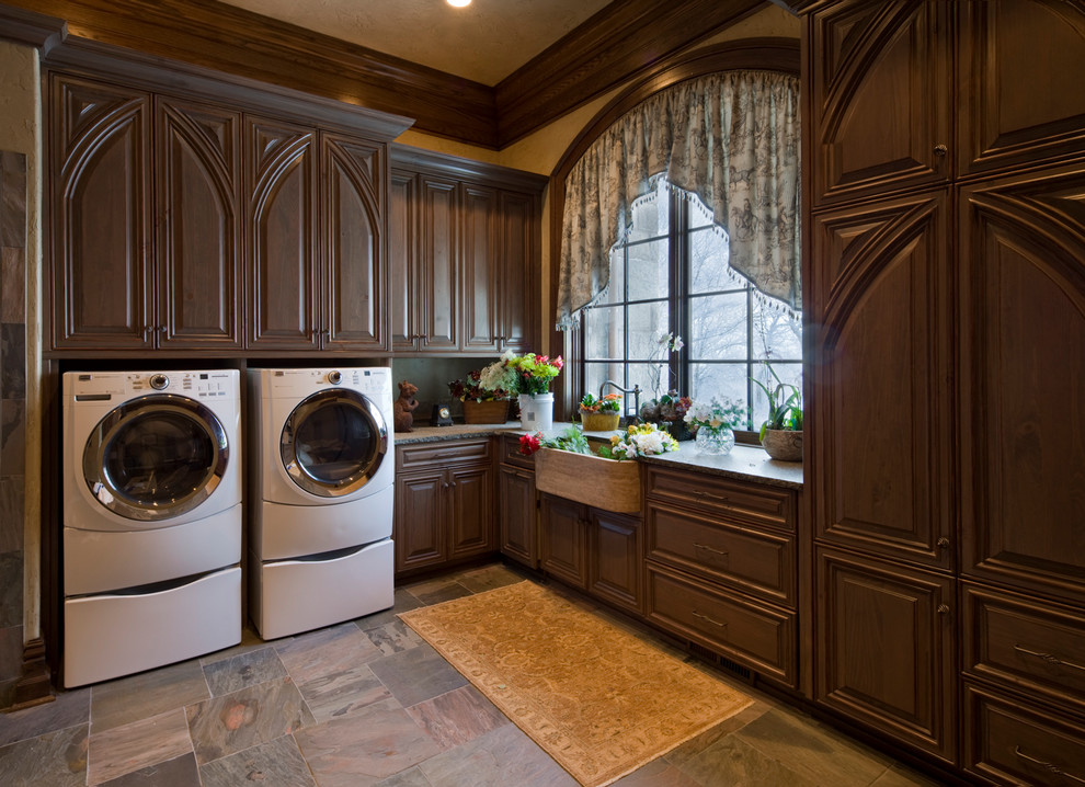 Geräumige Klassische Waschküche in L-Form mit profilierten Schrankfronten, Landhausspüle, dunklen Holzschränken und Granit-Arbeitsplatte in Charlotte