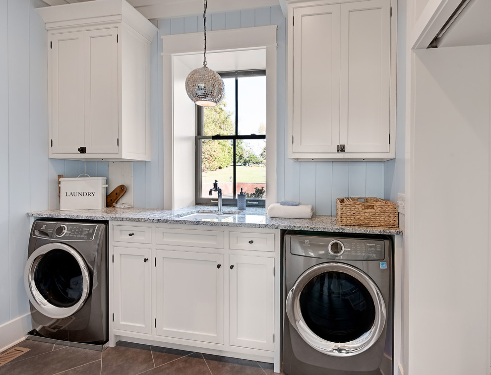 Ispirazione per una lavanderia stile marino di medie dimensioni con lavello sottopiano, ante bianche, top in granito, pareti blu, lavatrice e asciugatrice affiancate, pavimento grigio e ante a filo
