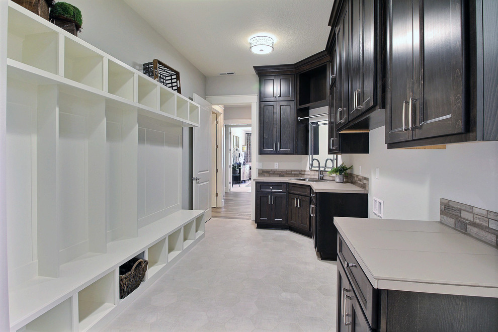 Example of a huge transitional galley ceramic tile and gray floor utility room design in Portland with a drop-in sink, recessed-panel cabinets, dark wood cabinets, tile countertops, white walls and a side-by-side washer/dryer