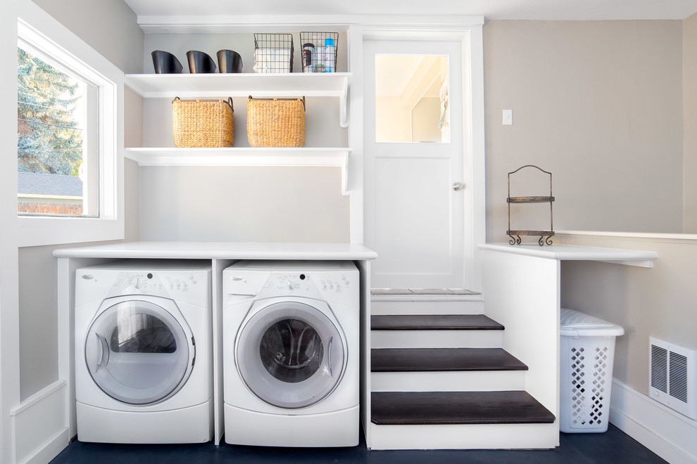 Dedicated laundry room - large transitional concrete floor and black floor dedicated laundry room idea in Boise with white cabinets, laminate countertops, a side-by-side washer/dryer, open cabinets, white countertops and gray walls