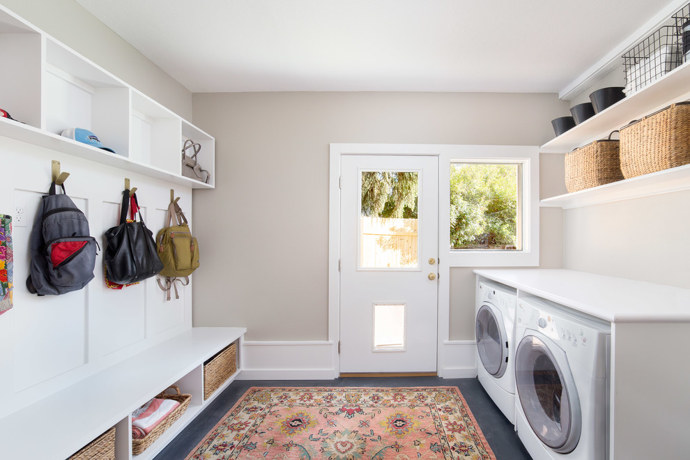 Inspiration for a large contemporary single-wall utility room in Boise with white cabinets, laminate countertops, concrete flooring, a side by side washer and dryer, black floors and grey walls.