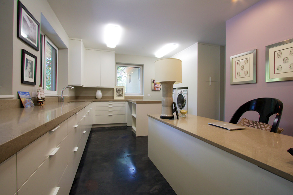 Large contemporary u-shaped utility room in Other with a single-bowl sink, flat-panel cabinets, white cabinets, engineered stone countertops, concrete flooring and a side by side washer and dryer.
