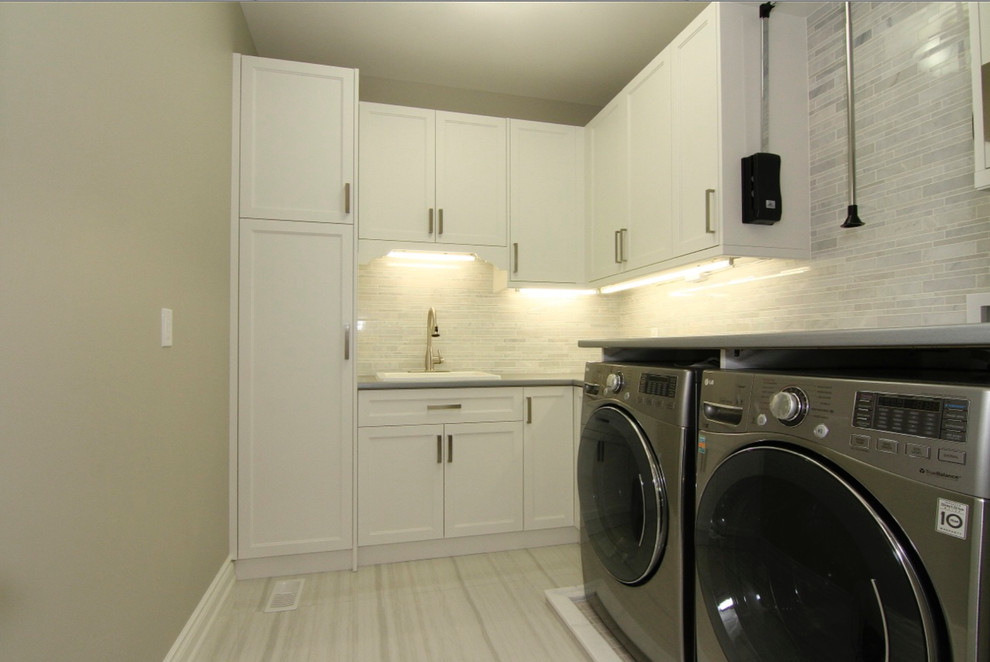 Idéer för att renovera en stor vintage parallell tvättstuga enbart för tvätt, med en enkel diskho, luckor med infälld panel, vita skåp, laminatbänkskiva, heltäckningsmatta, en tvättmaskin och torktumlare bredvid varandra och grå väggar