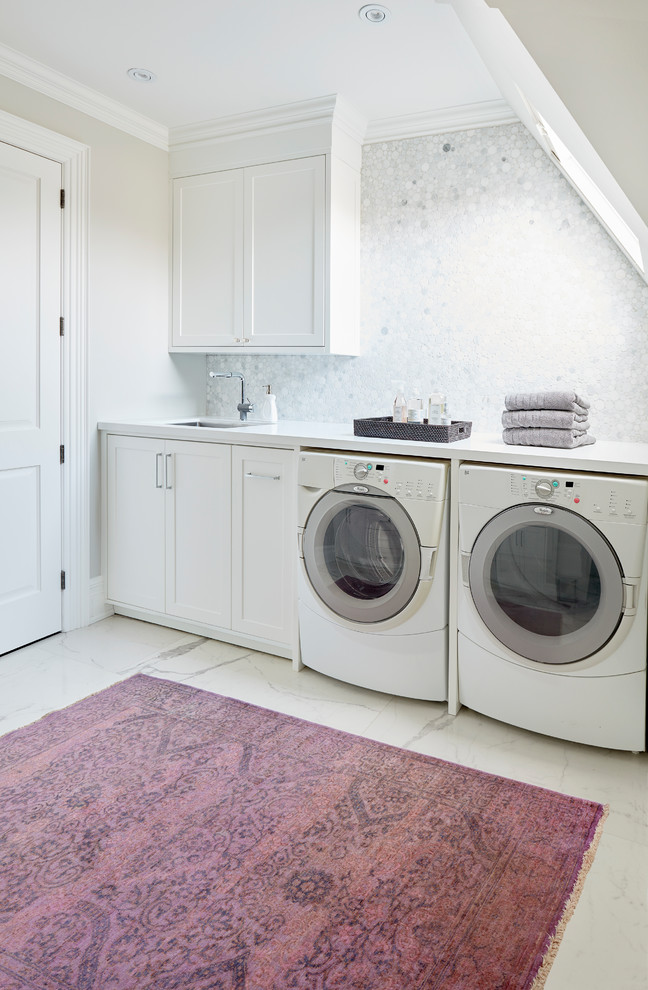 トロントにある高級な広いトランジショナルスタイルのおしゃれな洗濯室 (I型、アンダーカウンターシンク、落し込みパネル扉のキャビネット、白いキャビネット、クオーツストーンカウンター、グレーの壁、磁器タイルの床、左右配置の洗濯機・乾燥機、マルチカラーの床、白いキッチンカウンター) の写真