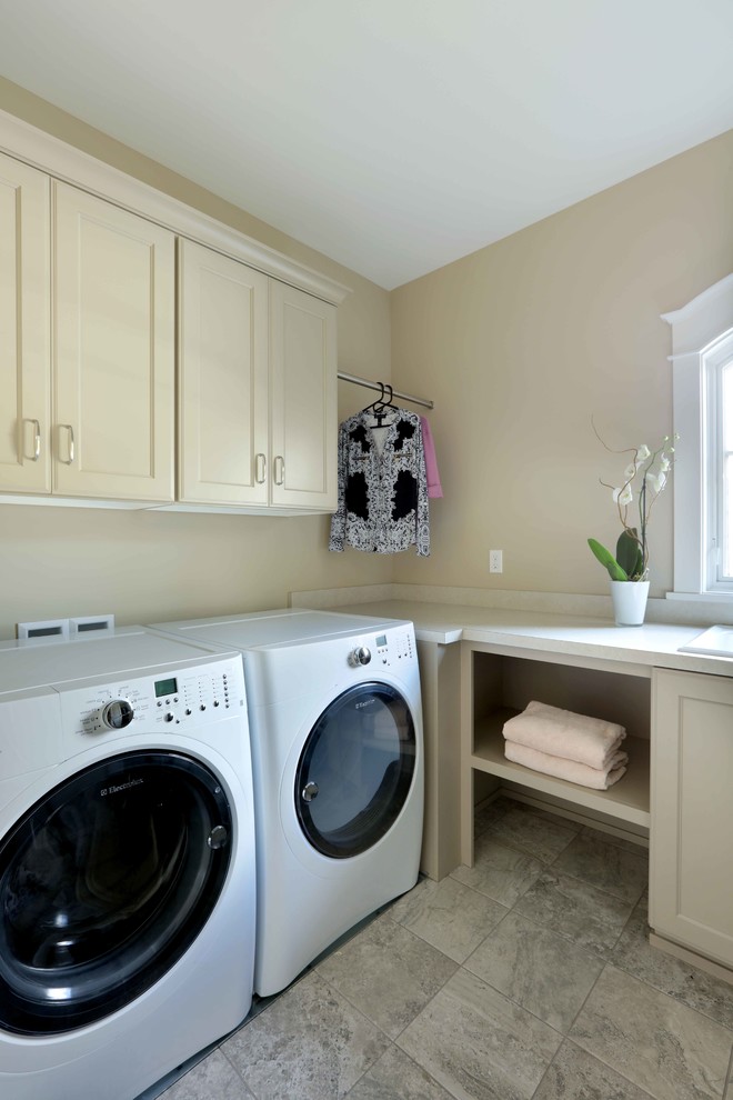 Rustikale Waschküche in U-Form mit Einbauwaschbecken, profilierten Schrankfronten, beigen Schränken, beiger Wandfarbe, Keramikboden, Waschmaschine und Trockner nebeneinander und buntem Boden in Grand Rapids