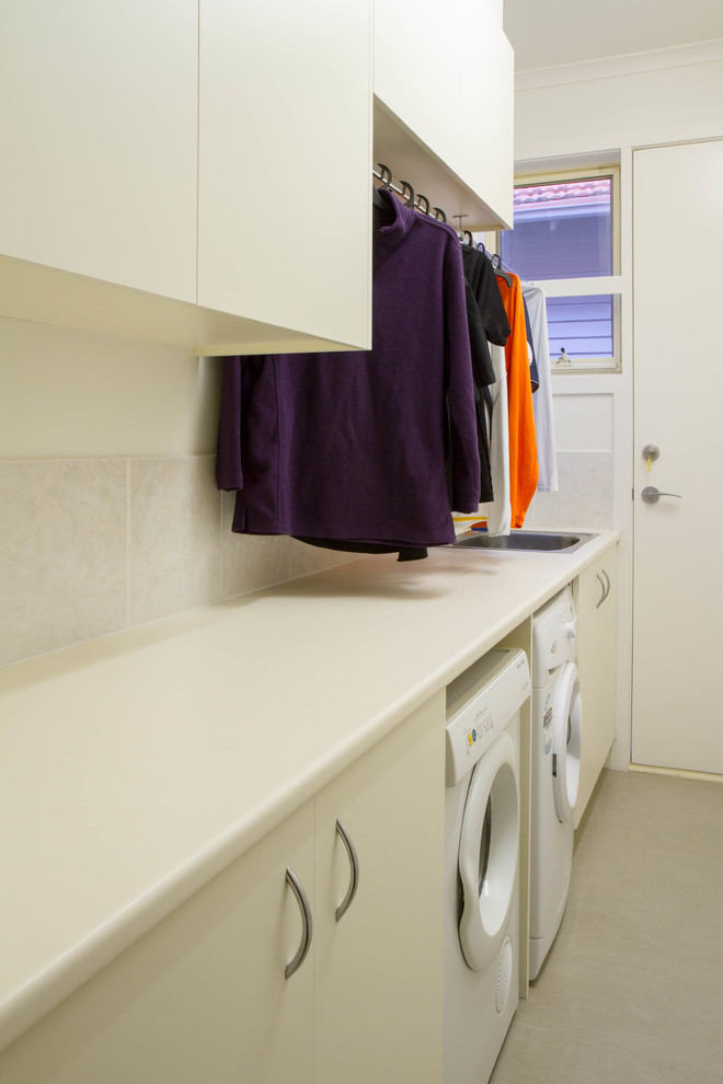 Imagen de cuarto de lavado de galera moderno de tamaño medio con fregadero de un seno, armarios con paneles lisos, puertas de armario blancas, encimera de laminado y lavadora y secadora juntas