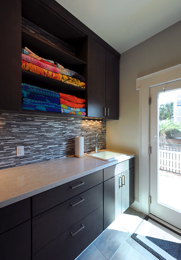 Large trendy galley ceramic tile laundry room photo in DC Metro with a drop-in sink, flat-panel cabinets, dark wood cabinets and quartz countertops