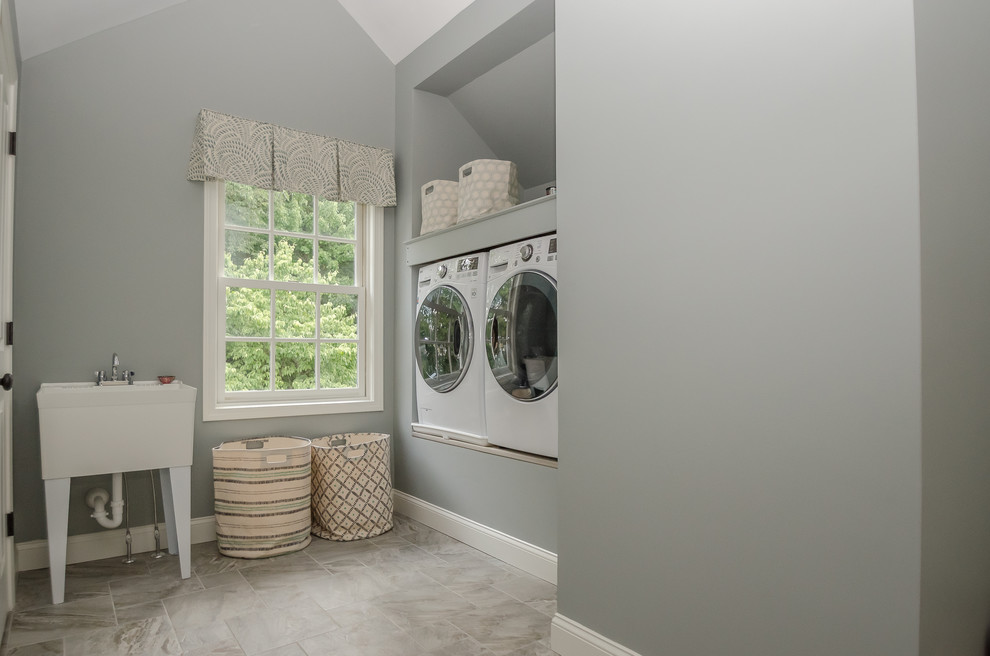 Foto de cuarto de lavado clásico de tamaño medio con pila para lavar, paredes grises, suelo de baldosas de porcelana y lavadora y secadora juntas
