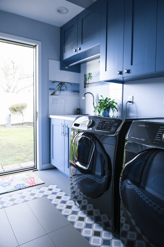Modern inredning av en mellanstor parallell tvättstuga enbart för tvätt, med en undermonterad diskho, skåp i shakerstil, blå skåp, blå väggar, klinkergolv i keramik och flerfärgat golv