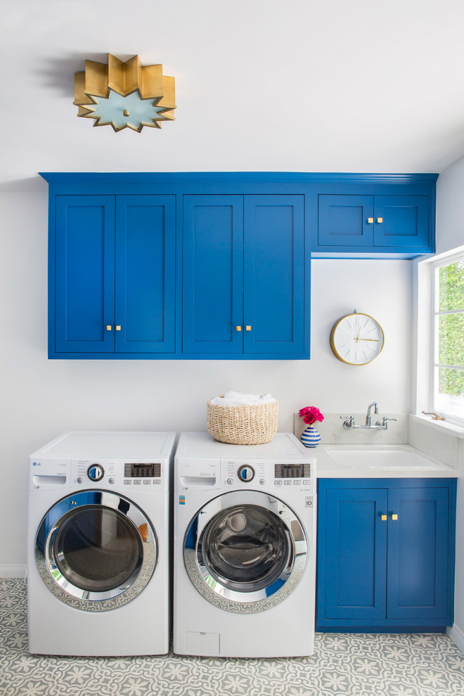 Esempio di una sala lavanderia tradizionale con lavello sottopiano, ante in stile shaker, ante blu, pareti grigie, lavatrice e asciugatrice affiancate e pavimento grigio