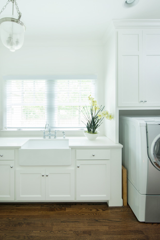 Foto på en lantlig tvättstuga, med en rustik diskho, skåp i shakerstil, vita skåp, vita väggar, mörkt trägolv och en tvättmaskin och torktumlare bredvid varandra