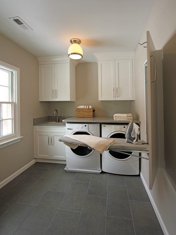 Photo of a large traditional single-wall separated utility room in DC Metro with recessed-panel cabinets, white cabinets, porcelain flooring, a side by side washer and dryer, a submerged sink and beige walls.