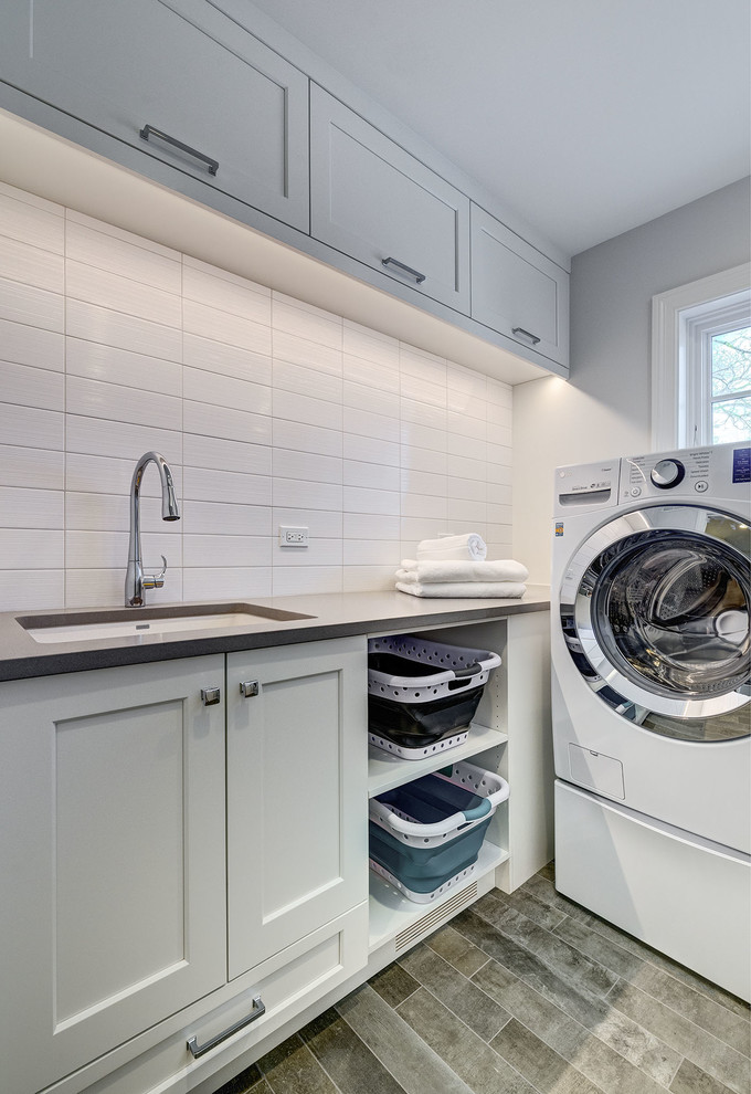 Mid-sized elegant galley porcelain tile and brown floor dedicated laundry room photo in Chicago with an undermount sink, flat-panel cabinets, white cabinets, quartzite countertops, white walls, a side-by-side washer/dryer and beige countertops