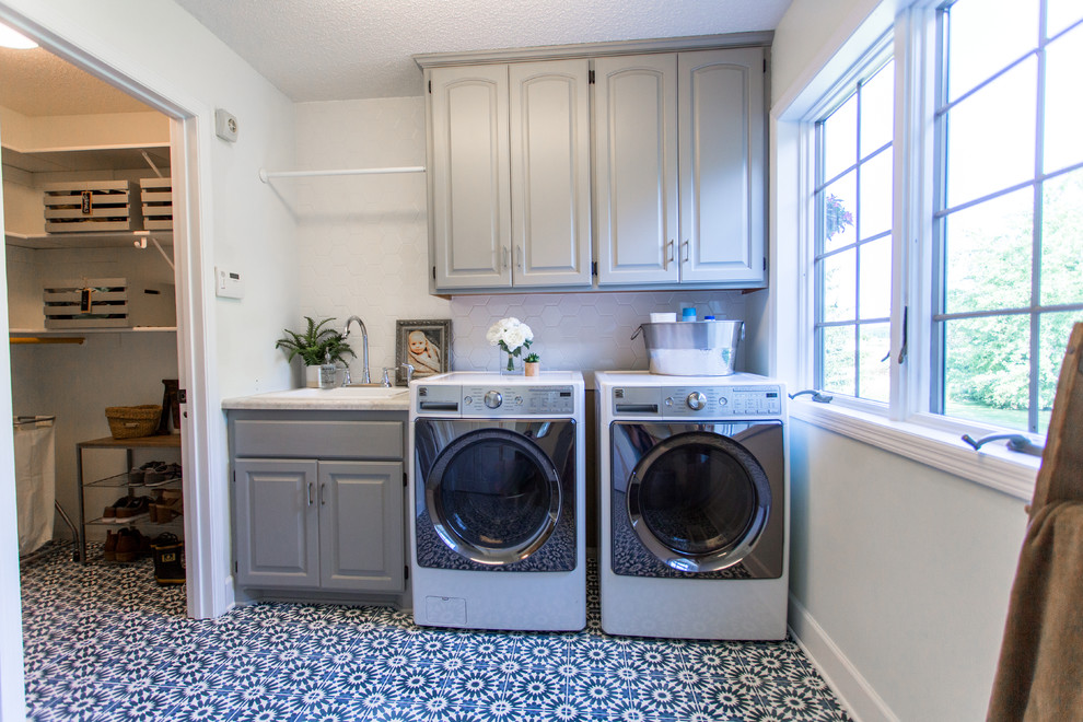 Idee per una grande sala lavanderia design con pavimento in cemento, lavatrice e asciugatrice affiancate, pavimento blu, lavello da incasso, ante con bugna sagomata e pareti grigie