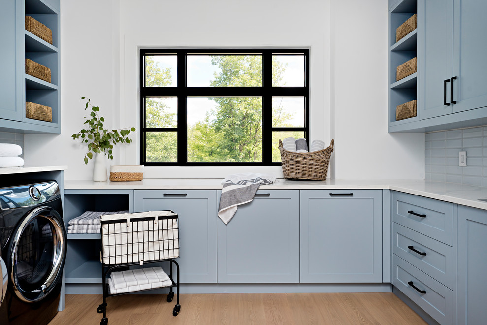 Esempio di una sala lavanderia classica con ante in stile shaker, ante blu, pareti bianche, pavimento in legno massello medio, lavatrice e asciugatrice affiancate, pavimento marrone e top bianco