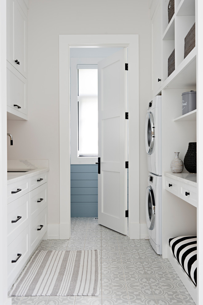 Design ideas for a traditional galley separated utility room in Toronto with a submerged sink, shaker cabinets, white cabinets, white walls, a stacked washer and dryer, multi-coloured floors and white worktops.