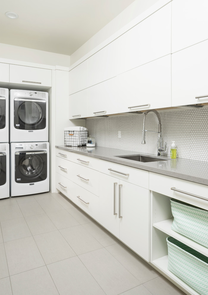 ソルトレイクシティにあるラグジュアリーな巨大なコンテンポラリースタイルのおしゃれなランドリールーム (白いキャビネット、上下配置の洗濯機・乾燥機、グレーのキッチンカウンター) の写真