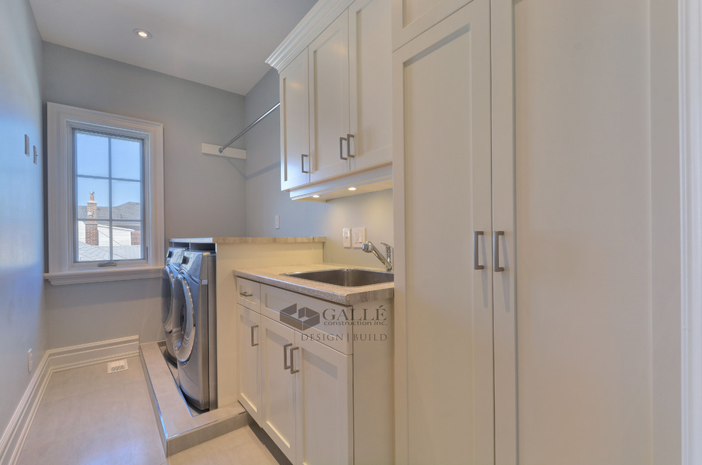 Inspiration for a large traditional l-shaped separated utility room in Toronto with a submerged sink, shaker cabinets, white cabinets, dark hardwood flooring, a side by side washer and dryer, engineered stone countertops and grey walls.