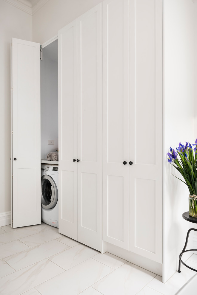 Imagen de armario lavadero lineal clásico renovado pequeño con armarios estilo shaker, puertas de armario blancas, encimera de cuarzo compacto, paredes blancas, suelo de baldosas de porcelana, lavadora y secadora juntas y suelo blanco