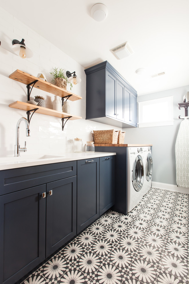 Idéer för mellanstora funkis linjära vitt tvättstugor enbart för tvätt, med en undermonterad diskho, skåp i shakerstil, blå skåp, bänkskiva i kvarts, blå väggar, betonggolv, en tvättmaskin och torktumlare bredvid varandra och blått golv