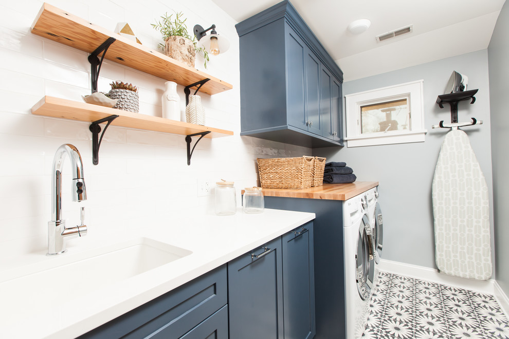 Immagine di una sala lavanderia minimalista di medie dimensioni con lavello sottopiano, ante in stile shaker, ante blu, top in quarzo composito, pareti blu, pavimento in cemento, lavatrice e asciugatrice affiancate, pavimento blu e top bianco