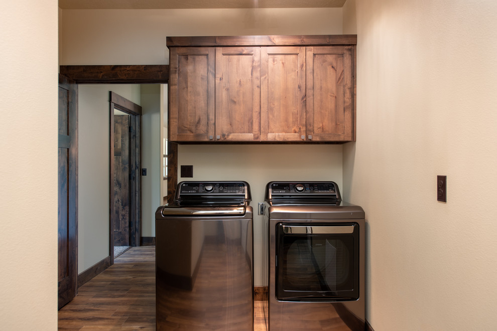 Foto di una piccola sala lavanderia rustica con ante a filo, ante in legno bruno, pareti beige, pavimento in legno massello medio, lavatrice e asciugatrice affiancate e pavimento marrone