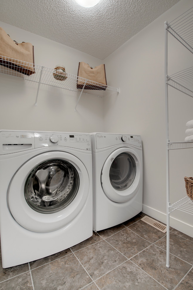 エドモントンにある低価格の小さなコンテンポラリースタイルのおしゃれな洗濯室 (I型、白い壁、テラコッタタイルの床、左右配置の洗濯機・乾燥機) の写真