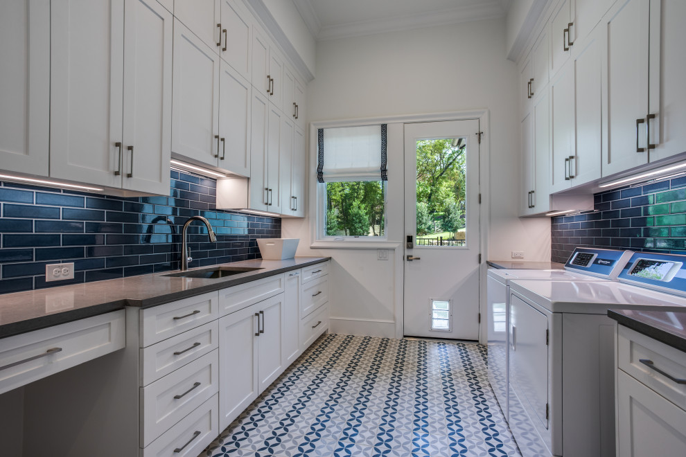 Photo of a large classic galley separated utility room in Dallas with a submerged sink, shaker cabinets, white cabinets, engineered stone countertops, blue splashback, ceramic splashback, white walls, concrete flooring, a side by side washer and dryer, multi-coloured floors and grey worktops.
