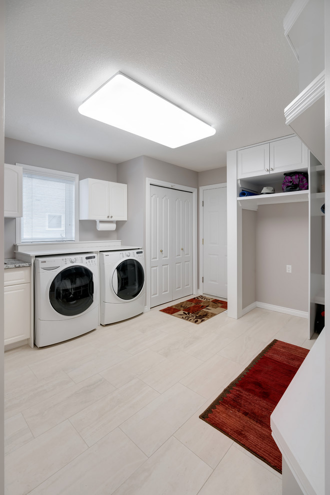 Photo of a medium sized modern u-shaped utility room in Edmonton with a submerged sink, shaker cabinets, white cabinets, grey walls, a side by side washer and dryer and white floors.