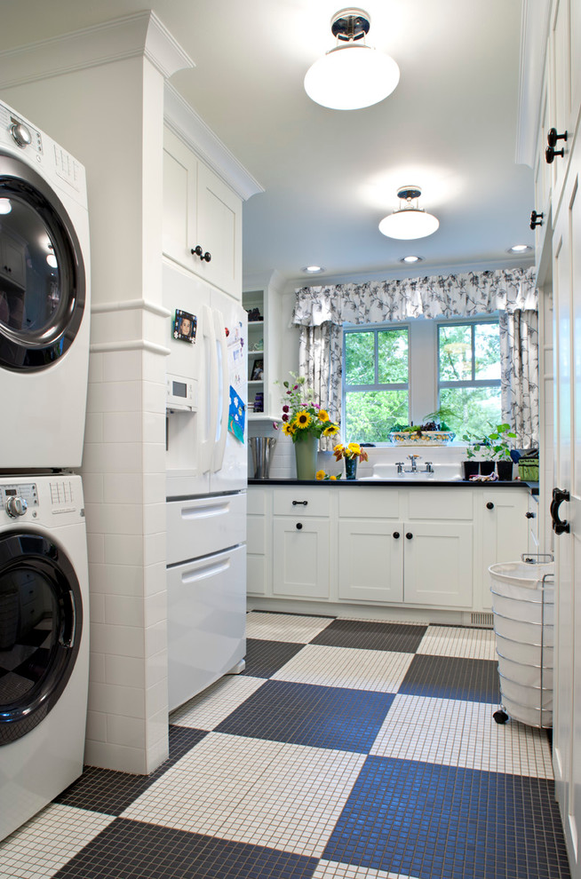 Ejemplo de lavadero tradicional con lavadora y secadora apiladas, puertas de armario blancas y suelo multicolor