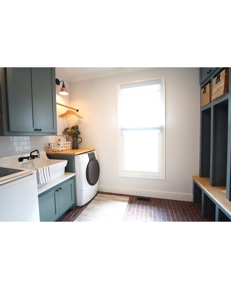 Inspiration for a mid-sized cottage galley brick floor and multicolored floor dedicated laundry room remodel in Philadelphia with a farmhouse sink, shaker cabinets, green cabinets, quartz countertops, gray walls, a side-by-side washer/dryer and white countertops