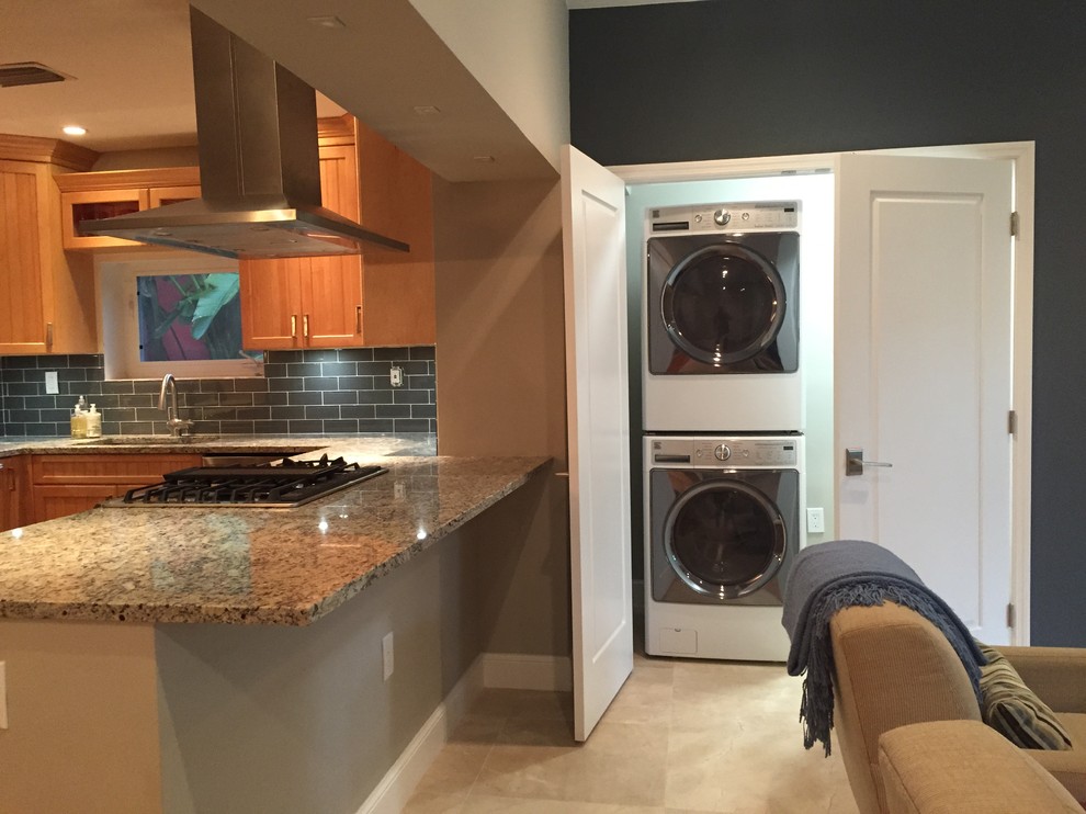 Example of a small trendy single-wall travertine floor laundry closet design in Miami with gray walls and a stacked washer/dryer