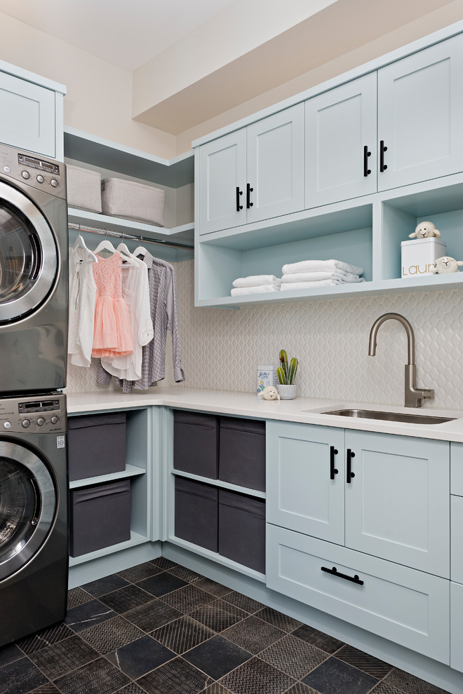 Esempio di una sala lavanderia country con lavello sottopiano, ante in stile shaker, ante blu, lavatrice e asciugatrice a colonna, pavimento marrone e top bianco