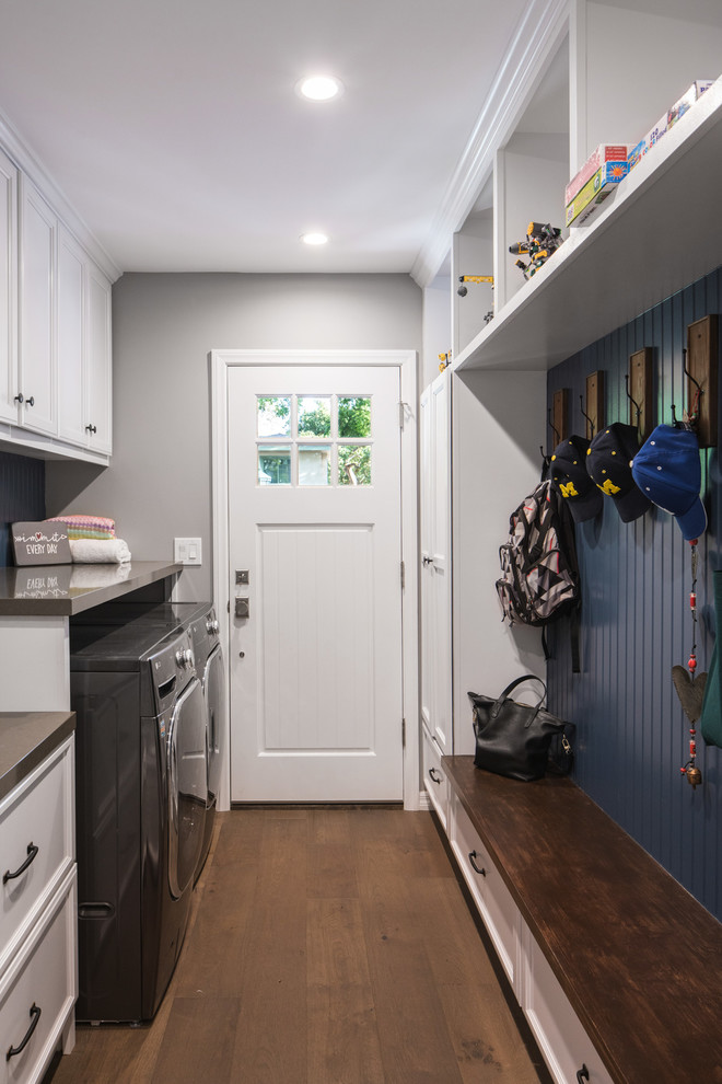 Example of a mid-sized transitional galley medium tone wood floor and brown floor dedicated laundry room design in Los Angeles with white cabinets, quartz countertops, blue walls and a side-by-side washer/dryer