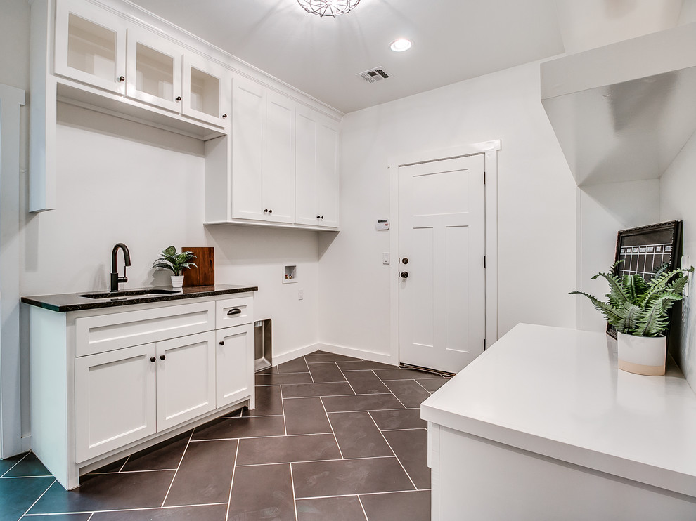 Inspiration for a large country single-wall ceramic tile and black floor utility room remodel in Oklahoma City with a drop-in sink, shaker cabinets, white cabinets, quartz countertops, white walls and a side-by-side washer/dryer