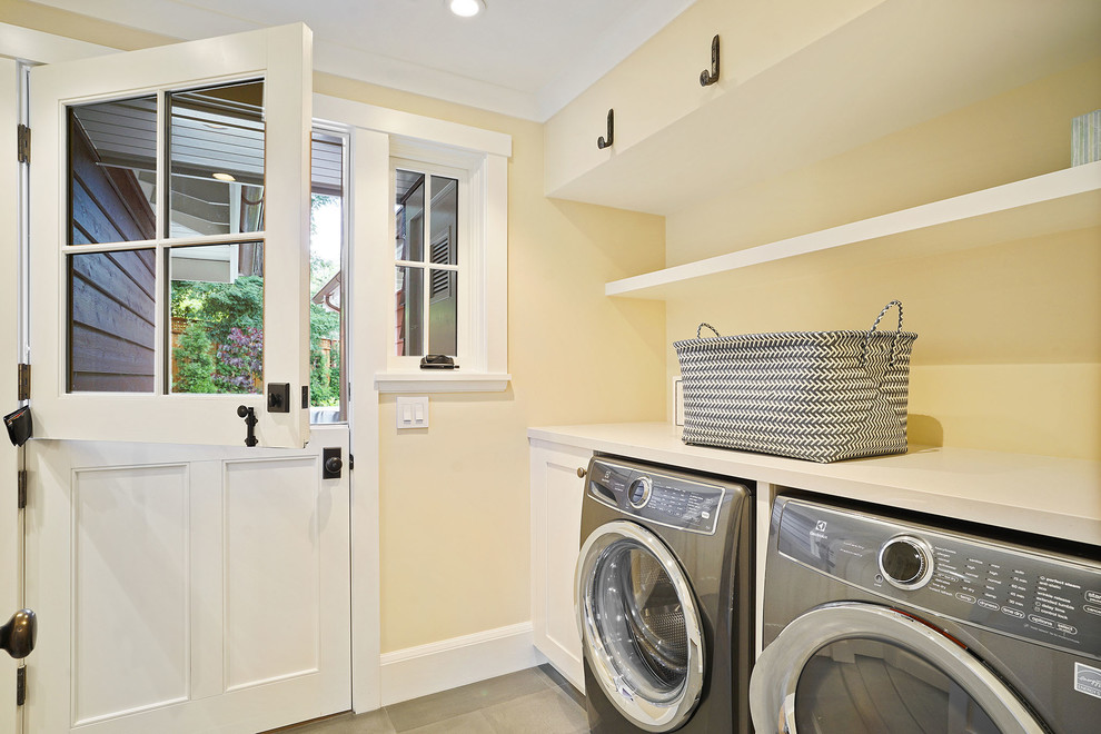 Foto di una grande sala lavanderia country con pareti gialle e lavatrice e asciugatrice affiancate