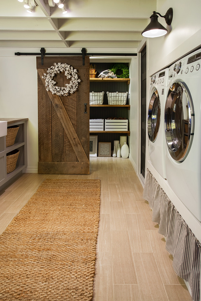Inredning av en lantlig mellanstor bruna parallell brunt tvättstuga enbart för tvätt, med en rustik diskho, skåp i shakerstil, grå skåp, träbänkskiva, vita väggar och en tvättmaskin och torktumlare bredvid varandra
