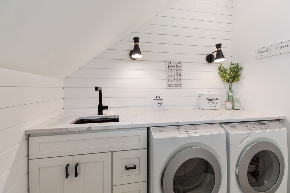 Bild på en lantlig flerfärgade linjär flerfärgat tvättstuga enbart för tvätt, med en undermonterad diskho, skåp i shakerstil, vita skåp, vita väggar, en tvättmaskin och torktumlare bredvid varandra och flerfärgat golv