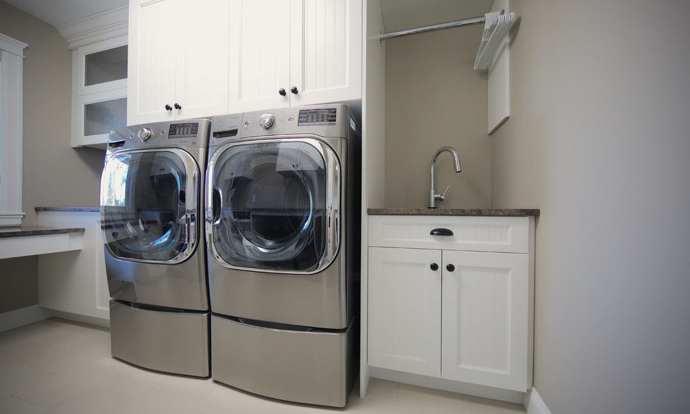 Exempel på en stor modern parallell tvättstuga enbart för tvätt, med en undermonterad diskho, skåp i shakerstil, vita skåp, granitbänkskiva, grå väggar, klinkergolv i keramik och en tvättmaskin och torktumlare bredvid varandra