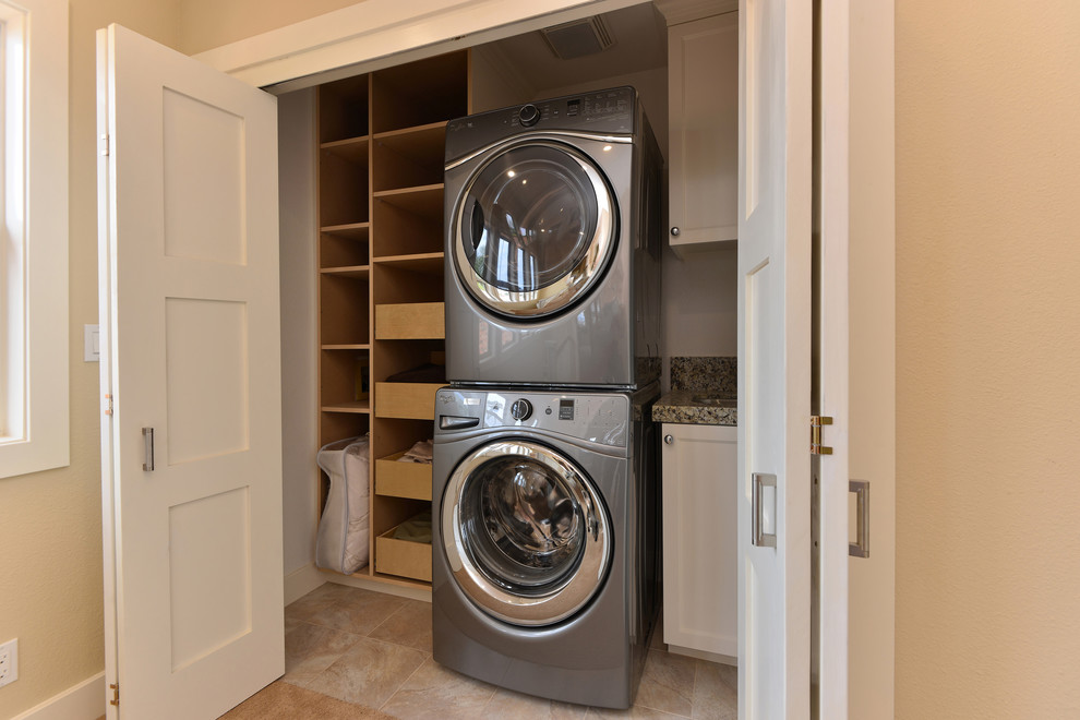 Example of a small beach style single-wall ceramic tile laundry closet design in San Diego with an undermount sink, shaker cabinets, white cabinets, granite countertops, white walls and a stacked washer/dryer