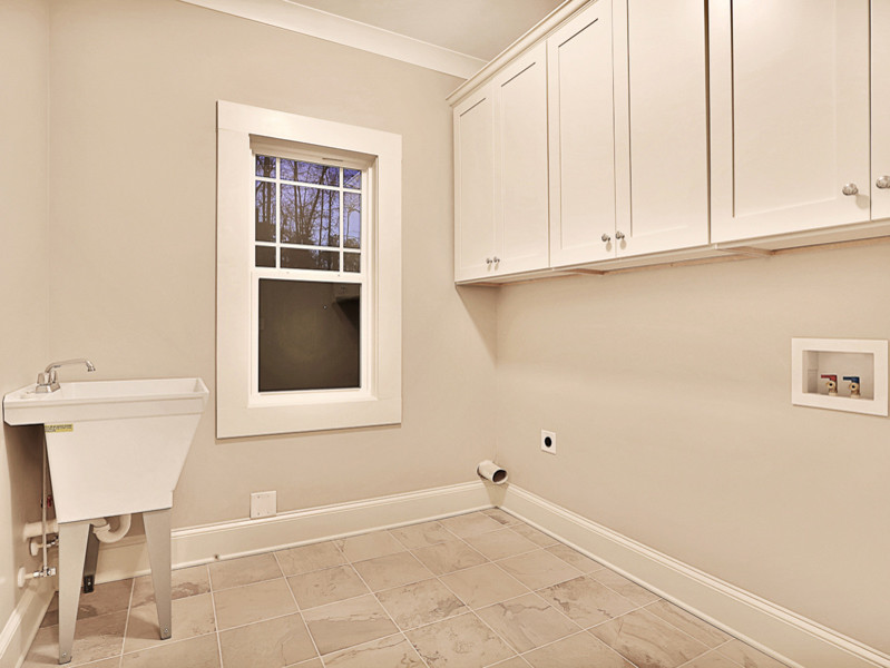 Photo of a medium sized traditional galley separated utility room in Atlanta with an utility sink, shaker cabinets, white cabinets, grey walls, ceramic flooring and a side by side washer and dryer.
