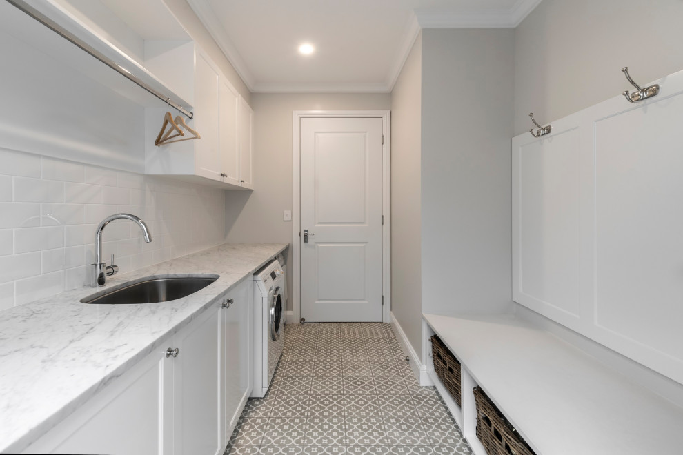 Nautical galley separated utility room with a submerged sink, a side by side washer and dryer and grey worktops.